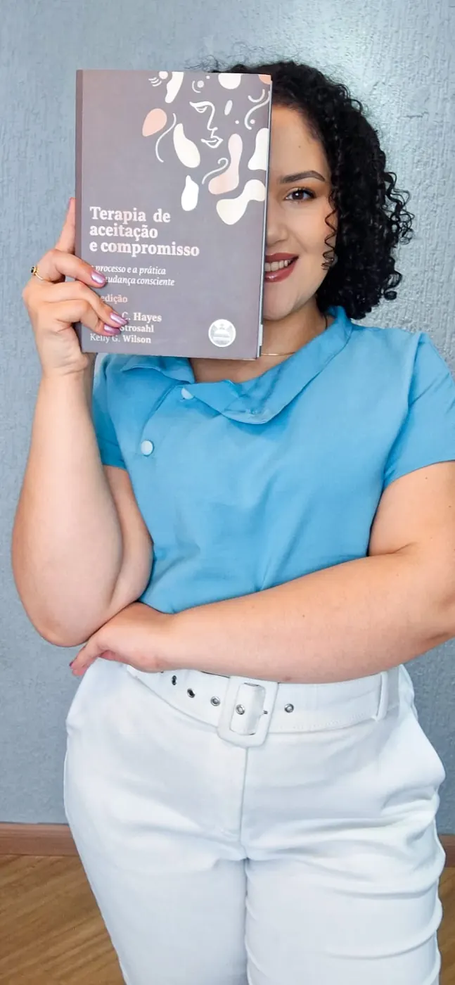 Laryssa Guedes segurando um livro sobre Terapia de Aceitação e Compromisso